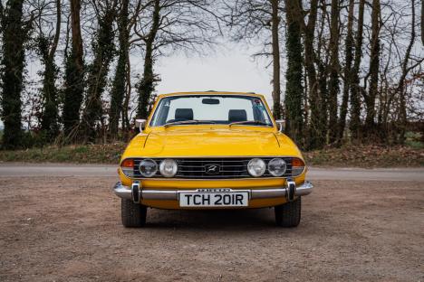 Yellow 1977 Triumph Stag convertible.