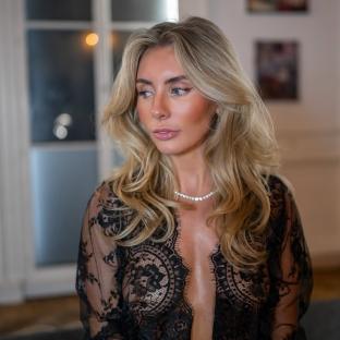 Woman with long blonde hair wearing a black lace robe.