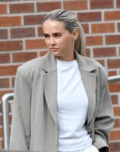 Woman in a pinstripe blazer and white pants.