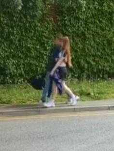 Two people walking down a sidewalk.