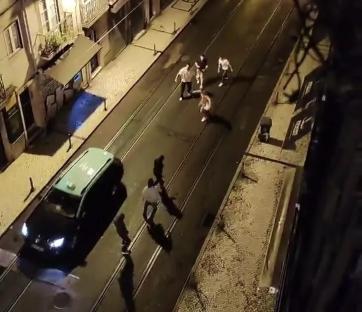 Overhead view of a street at night showing a group of people and a taxi.