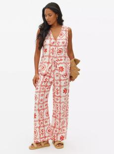Woman wearing a red and white patterned pantsuit.