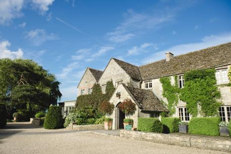 Stone building with ivy covered walls and manicured hedges.