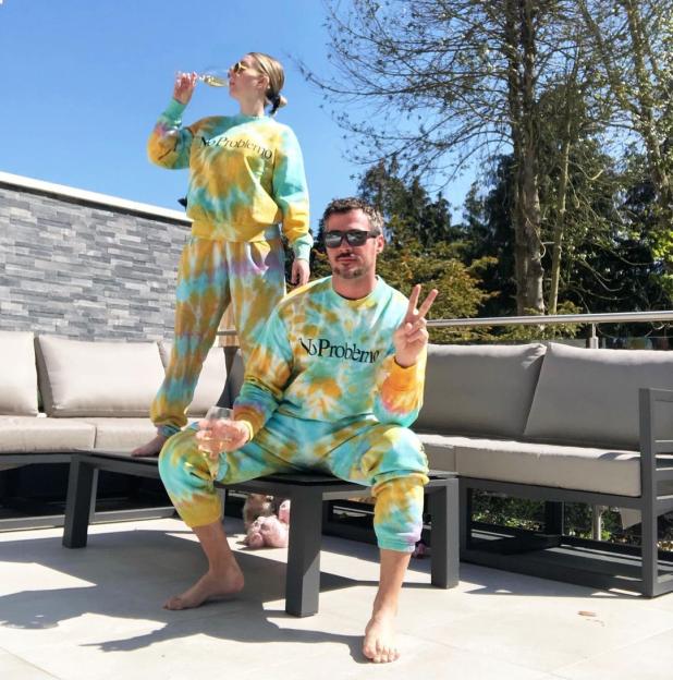 Katherine Ryan and her husband in matching tie-dye loungewear with "No Problemo" text.