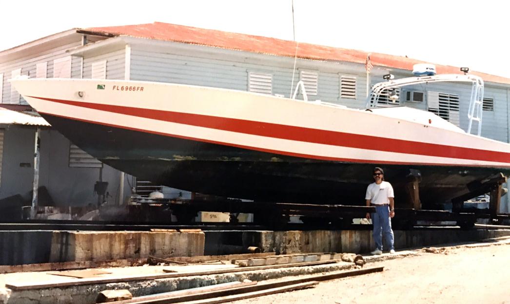 A man standing beside a large boat on a dry dock.