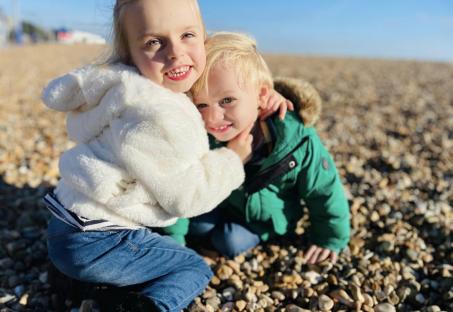 Two young children hugging on a beach.