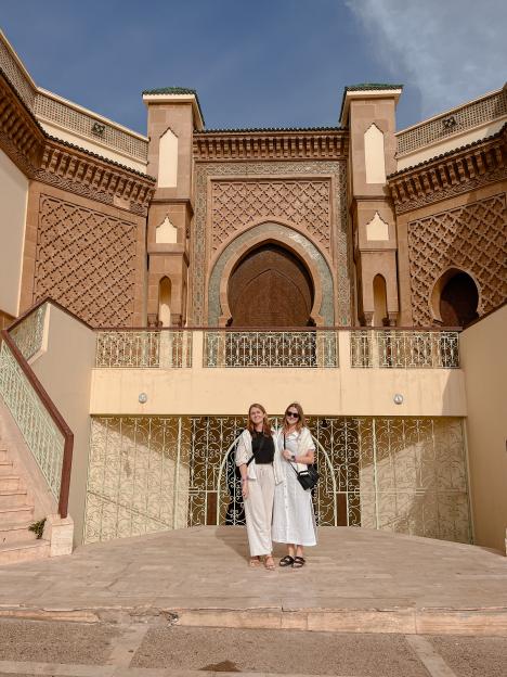 Two women posing in front of a mosque.