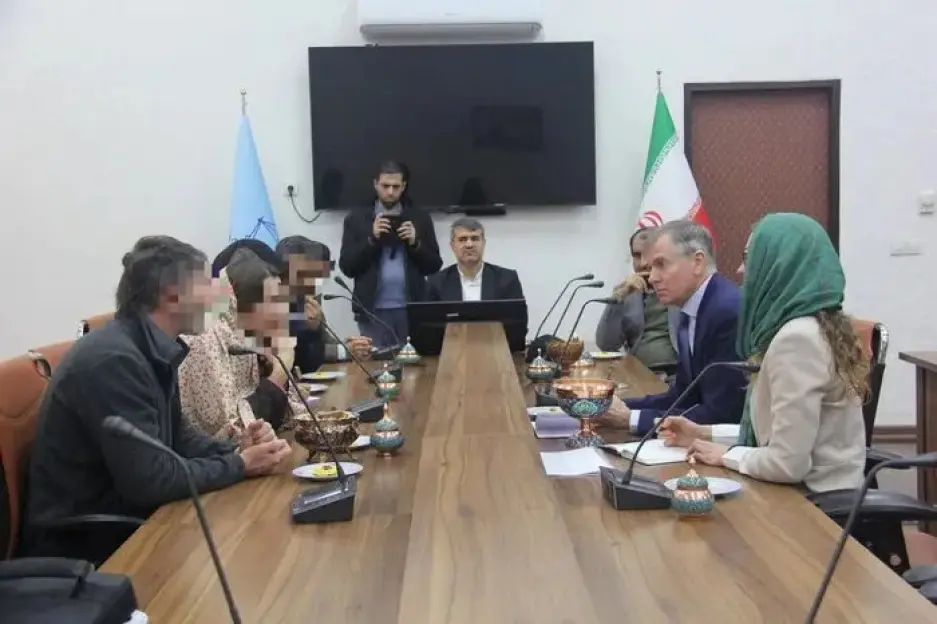 Meeting of people seated around a long table.