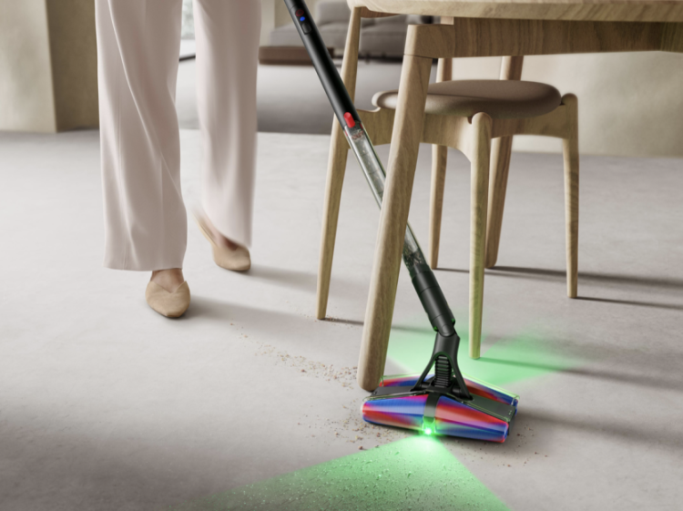 Person using a Dyson vacuum to clean under a table.