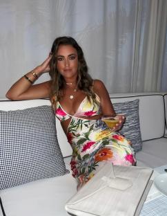 Georgina Leigh Cantwell in floral dress, holding a cocktail.