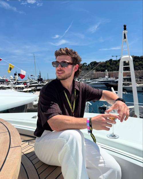 George Clarke on a yacht, holding a glass of wine.