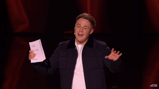 A man holding a stack of papers on stage.