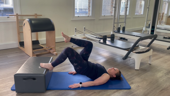 Woman performing a Pilates leg exercise.