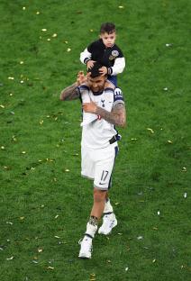 Cristian Romero of Tottenham Hotspur celebrates a Europa League victory with his son on his shoulders.