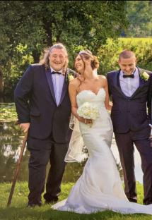 A bride and groom with the bride's father at their wedding.