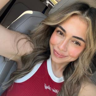 Woman with long brown hair smiling in a car.