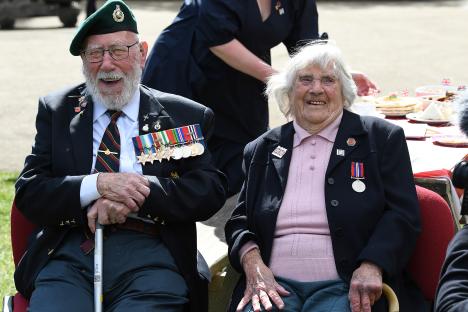 Two smiling WWII veterans, John Eskdale and Jean Green, wearing medals.