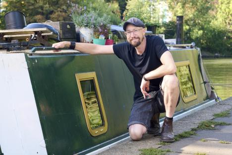 Man kneeling by a canal boat.