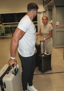 Molly Mae and Tommy Fury arriving at an airport with luggage.
