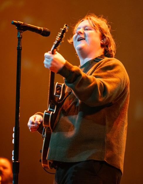 Lewis Capaldi performing on stage with a guitar.
