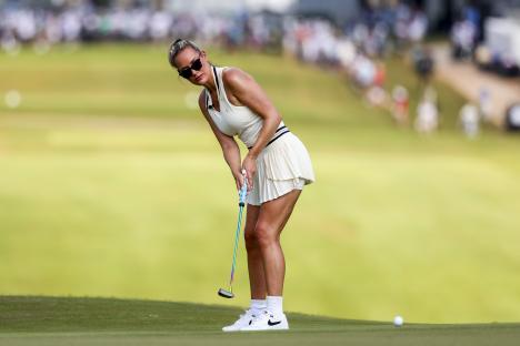 Paige Spiranac watches a putt on a golf course.