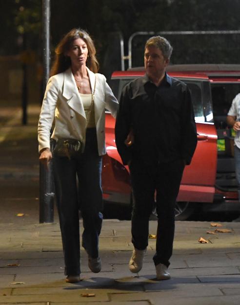 Noel Gallagher and Sally Mash walking down the street at night.