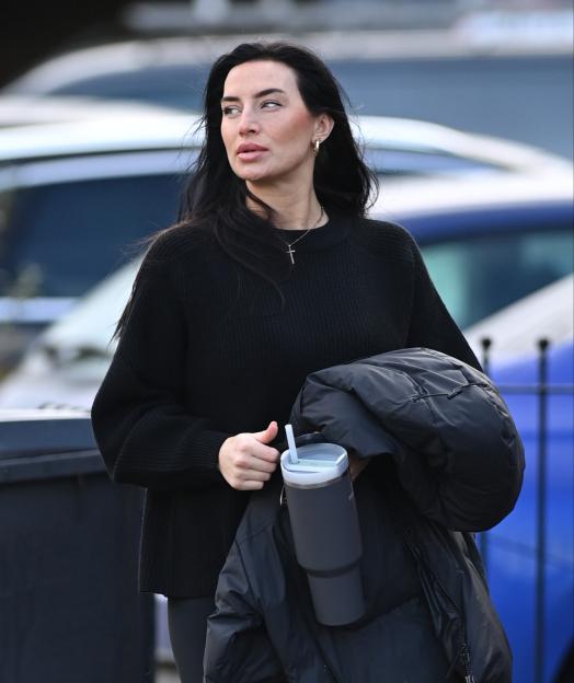 Annie Kilner walking to the gym, carrying a coat and a drink.