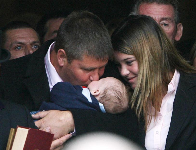 A man kisses a baby at a funeral.
