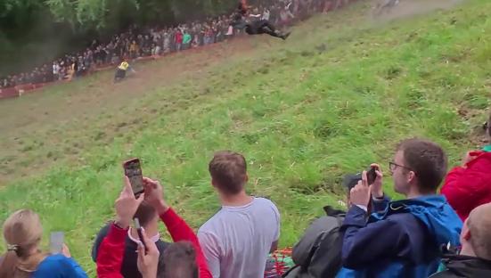 Person backflipping down a hill at a cheese rolling competition.