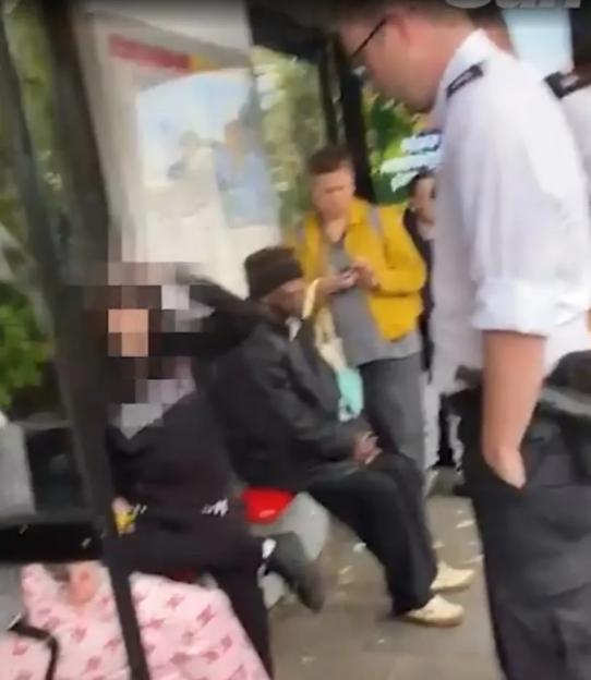 A group of young people gathered on a sidewalk, one with blurred face holding stolen clothes.