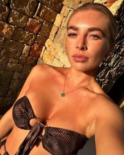 Woman in a brown bikini top against a stone wall.
