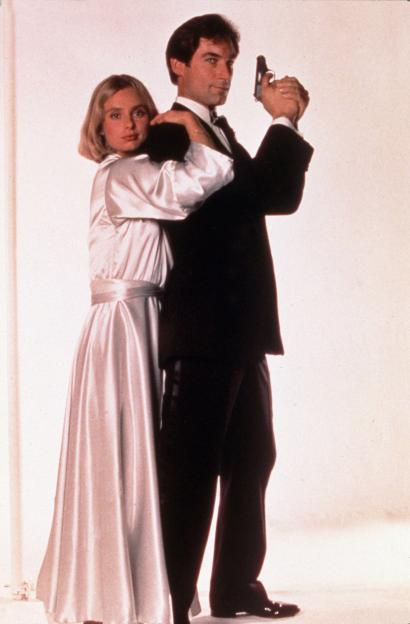 Timothy Dalton as James Bond holding a gun, with Maryam D'Abo behind him in "The Living Daylights."