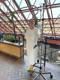 Young woman in a hospital gown receiving IV treatment.