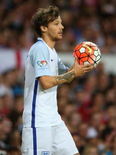 Louis Tomlinson holding a soccer ball at a Soccer Aid match.