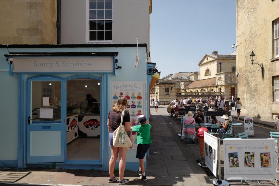 People looking at an ice cream shop menu in Bath, England.
