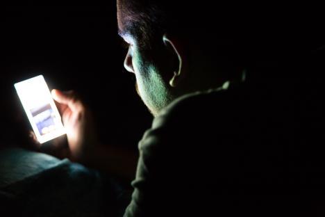 Man using smartphone in bed at night.