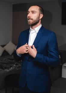 Man in a blue suit adjusting his jacket.