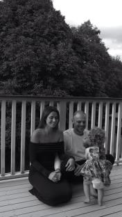 Black and white photo of a family of three on a deck.