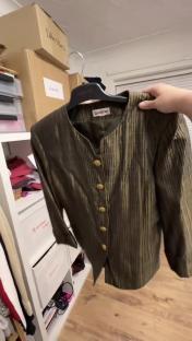 A green jacket with gold buttons hanging on a rack.