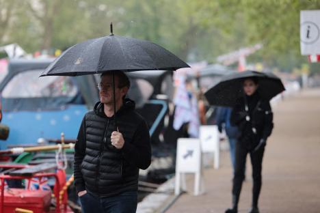 People with umbrellas walking in the rain at a canal festival.