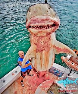 Man holding a large shark on a boat.