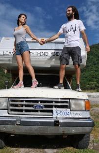 Couple standing on the hood of their campervan.