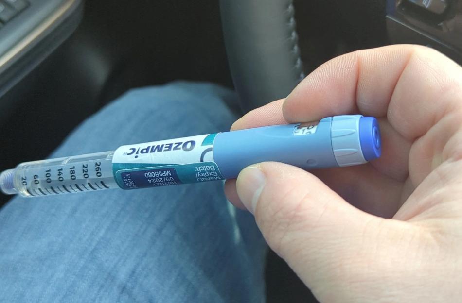 Hand holding a suspected counterfeit Ozempic pen.