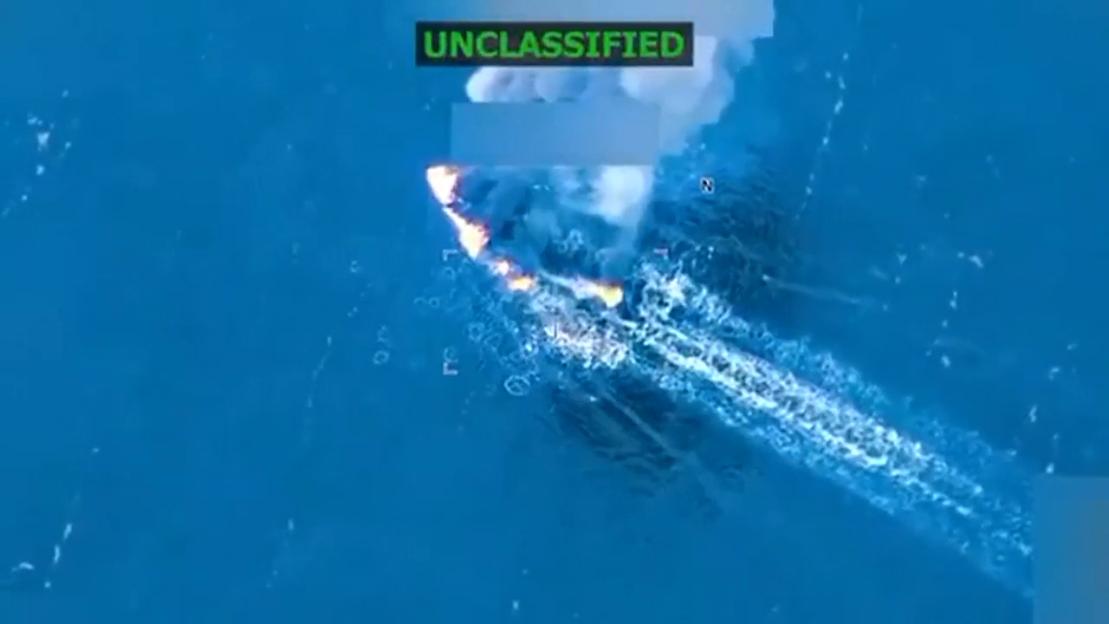 Aerial view of a boat on fire in the ocean, with a label "UNCLASSIFIED" at the top.