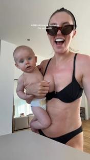 Woman holding baby, wearing sunglasses and a black bikini top.