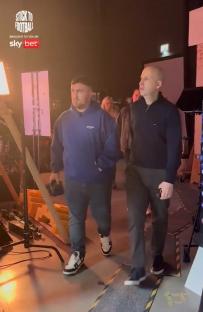Behind-the-scenes photo of two men walking on a film set.