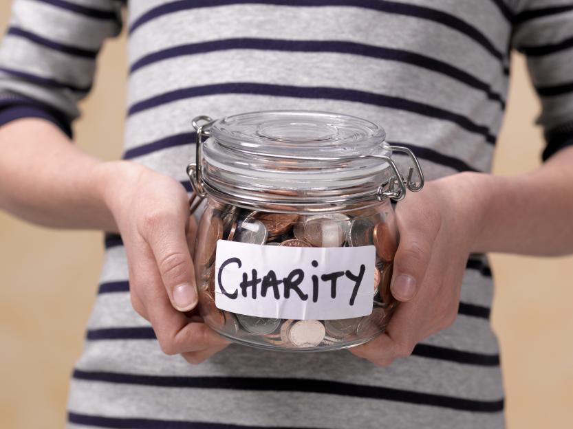 Child holding a jar of coins labeled "Charity."