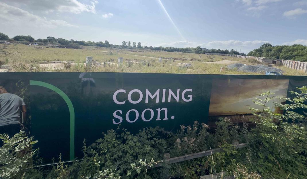 "Coming soon" sign in front of a vacant lot.