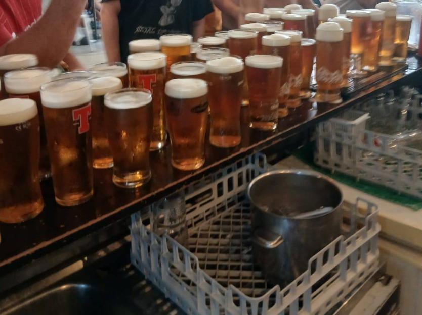 Many pints of beer on a bar counter.