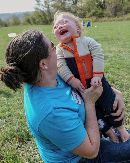 Hannah holding baby Liam, who is laughing and wearing a multi-colored jacket.